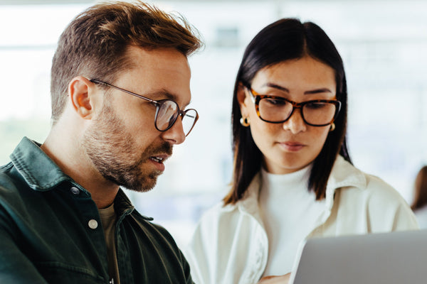 Two people looking at a laptop together in an indoor setting